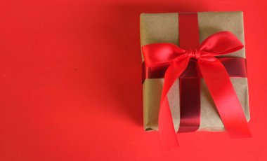 El işi kağıdına sarılı Noel hediyeleri, kırmızı arka planda el yapımı hediyeler. Noel hediyeleri ve kırmızı Noel yayları. Bayram havasından bir hediye. Yeni yıl Noel dekoru. 
