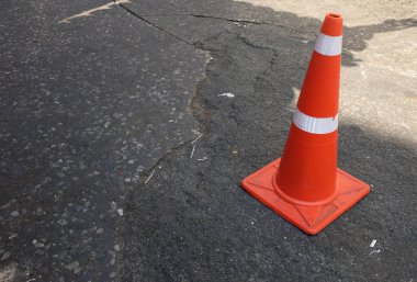Yol yüzeyinde tek başına duran parlak turuncu trafik konisi, şehir caddelerinde çalışma alanı. Trafik işaretleri yol inşaatlarında yavaş olduğunu gösteriyor.. 