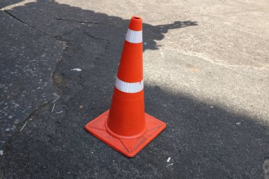 Bright orange traffic cone standing alone on the road surface,Work area on city streets.Traffic signs indicating that it is slow at road construction sites.  clipart