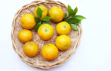 Taze ve sulu portakal, mandalina, portakal, portakal balı, Tayland portakalı (Citrus reticulata) ve yeşil yaprak yığını beyaz bir sırt üstü izole edilmiş ahşap sepetin içinde. C vitamini ile sağlıklı meyveler..