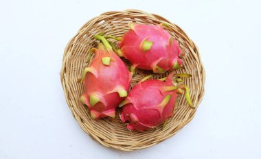 Taze olgun pembe bir ejderha meyvesini, pitaya 'yı (hylocercus undatus) beyaz arka planda izole edilmiş ahşap bir sepete koy. Sağlıklı yiyecek ve meyve kavramı.
