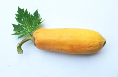 Üst ve düz bir zemin üzerinde yeşil yapraklı, dilimlenmiş, olgun bir papaya meyveli papaya uzanır. Sağlıklı beslenme için sebze ve meyve.