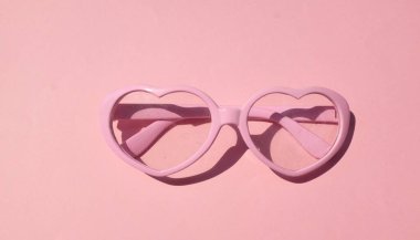 Pembe güneş gözlükleri, pembe renkli arka planda modern modaya uygun kalp şeklinde. Mesajın için. Aşk mesajı, Aşk romantik, Modern Moda ve Sevgililer Günü kompozisyonu