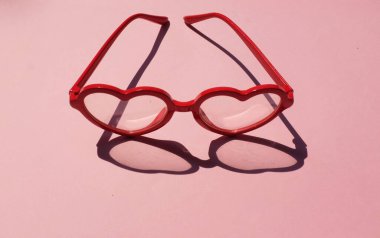  Kırmızı güneş gözlüklü, modern modaya uygun kalp şeklinde pembe pastel arka planda. Mesajın için. Aşk mesajı, Aşk romantik, Modern Moda ve Sevgililer Günü kompozisyonu