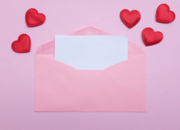 розовый конверт бумаги с пустой белой нотой макет внутри и декоративная красная форма сердца, ручка красного цвета на розовой пастели backdrop.for текст. любовное послание, Любовь романтические, канцелярские принадлежности и День Святого Валентина 