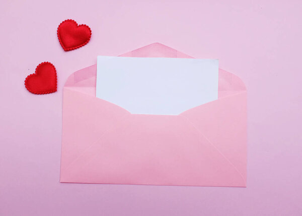 розовый конверт бумаги с пустой белой нотой макет внутри и декоративная красная форма сердца, ручка красного цвета на розовой пастели backdrop.for текст. любовное послание, Любовь романтические, канцелярские принадлежности и День Святого Валентина 