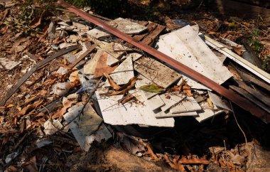 Üst ve düz bir ahşap yığını var. Atık odun yığını. İnşaat, yıkım ve çöpten kalma eski bir odun yığını. Çivili, kıymıklı, kablolu ve çöplü büyük bir çöp yığını. Çöp yığını.