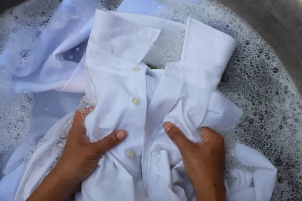 Asyalı ev hanımının beyaz giysileri yıkaması, kirli gömlek yakası, beyaz gömlek, beyaz takım elbise, leğende köpük deterjanı olan öğrenci üniformaları. Çamaşır konsepti.