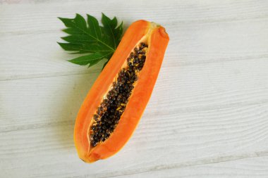 Masanın üzerinde yeşil yapraklı, yarı olgun papaya meyvesi. Sağlıklı beslenme için meyve ve sebze. Vejetaryen diyeti..
