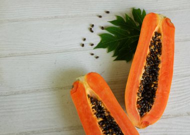 Masanın üzerinde yeşil yapraklı, yarı olgun papaya meyvesi. Sağlıklı beslenme için meyve ve sebze. Vejetaryen diyeti..