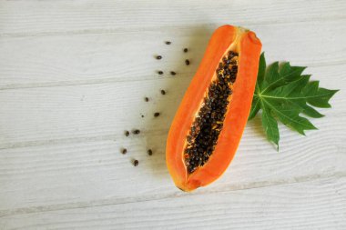 Masanın üzerinde yeşil yapraklı, yarı olgun papaya meyvesi. Sağlıklı beslenme için meyve ve sebze. Vejetaryen diyeti..