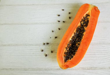 Masanın üzerinde yeşil yapraklı, yarı olgun papaya meyvesi. Sağlıklı beslenme için meyve ve sebze. Vejetaryen diyeti..