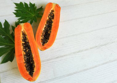 Masanın üzerinde yeşil yapraklı, yarı olgun papaya meyvesi. Sağlıklı beslenme için meyve ve sebze. Vejetaryen diyeti..