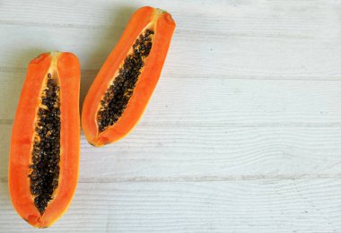 Masanın üzerinde yeşil yapraklı, yarı olgun papaya meyvesi. Sağlıklı beslenme için meyve ve sebze. Vejetaryen diyeti..