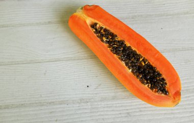 Masanın üzerinde yeşil yapraklı, yarı olgun papaya meyvesi. Sağlıklı beslenme için meyve ve sebze. Vejetaryen diyeti..