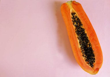 Yarı olgun, yeşil yapraklı papaya meyvesi. Pembe pastel bir sırt damlasına izole edilmiş. Sağlıklı beslenme için meyve ve sebzeler..