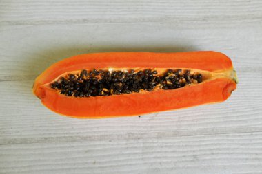 Masanın üzerinde yeşil yapraklı, yarı olgun papaya meyvesi. Sağlıklı beslenme için meyve ve sebze. Vejetaryen diyeti..