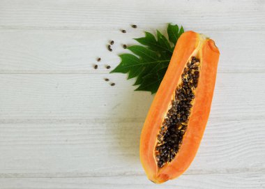 Masanın üzerinde yeşil yapraklı, yarı olgun papaya meyvesi. Sağlıklı beslenme için meyve ve sebze. Vejetaryen diyeti..