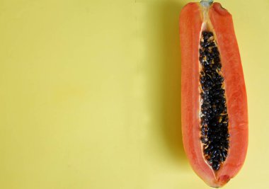 Sarı pastel sırt damlasına ayrılmış yeşil yapraklı yarı olgun papaya meyvesi. Sağlıklı beslenme için meyve ve sebze. Vejetaryen diyeti.