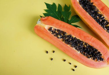 Sarı pastel sırt damlasına ayrılmış yeşil yapraklı yarı olgun papaya meyvesi. Sağlıklı beslenme için meyve ve sebze. Vejetaryen diyeti.
