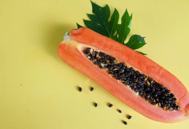 Sarı pastel sırt damlasına ayrılmış yeşil yapraklı yarı olgun papaya meyvesi. Sağlıklı beslenme için meyve ve sebze. Vejetaryen diyeti.