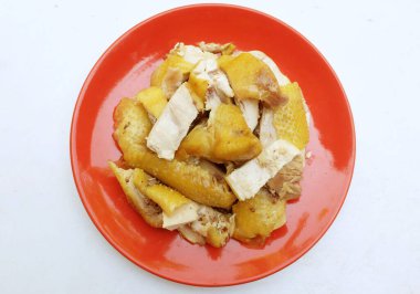 Sarı haşlanmış tavuk kırmızı bir tabakta parçalara bölünmüş ve beyaz bir arka planda izole edilmeye hazır. Tayland yemeği..