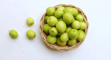 Taze taze taze yeşil sulu süt jujubası, kuyruklu süt jujubası, Hint jube meyvesi (ziziphus juba değirmeni) meyve, hasırdan bir sepette ikiye bölünmüş süt jubası beyaz bir arka planda izole edilmiş.