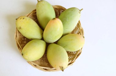 Taze organik Barakuda Mango, Nam Dok Mai, Altın Mango, Sarı Mango (Mangifera indica Linn). Hasır bir sepetteki mango meyveleri beyaz bir zeminde izole edilmiş yapraklarla. Tayland 'da tropik meyve ve egzotik