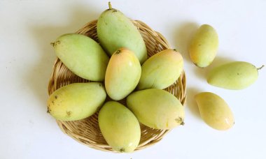Taze organik Barakuda Mango, Nam Dok Mai, Altın Mango, Sarı Mango (Mangifera indica Linn). Hasır bir sepetteki mango meyveleri beyaz bir zeminde izole edilmiş yapraklarla. Tayland 'da tropik meyve ve egzotik