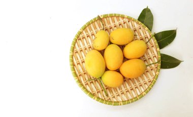 Taze taze olgun Marian erik mayonezi, akçaağaç eriği ve erik mangosu (Bouea tabağı zıt tabaka) ve yaprakları beyaz zemin üzerinde izole edilmiş ahşap rattan tabaklarda yatar. Tropik meyve Tayland ve sağlıklı 