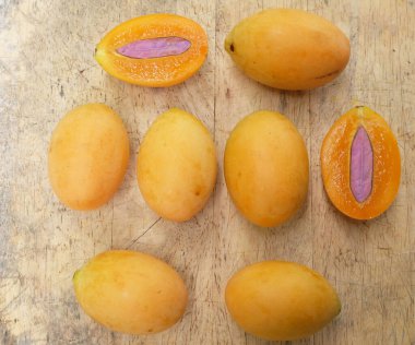 Üst ve düz taze taze tatlı olgun Marian erik yığını Tayland meyvesi bir ahşap zemin üzerinde izole (mayongchid maprang marian erik ve erik mango, thailand) yatıyordu. Tayland 'ın sağlıklı meyveleri.