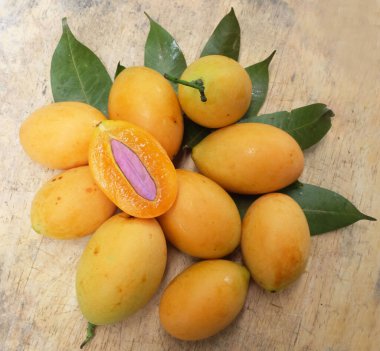 Üst ve düz taze taze tatlı olgun Marian erik yığını Tayland meyvesi bir ahşap zemin üzerinde izole (mayongchid maprang marian erik ve erik mango, thailand) yatıyordu. Tayland 'ın sağlıklı meyveleri.