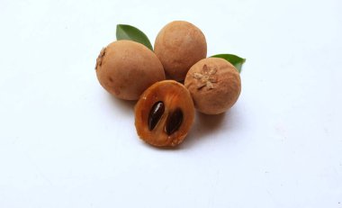 Yarı kesilmiş ve yeşil yapraklı bir grup taze organik tatlı meyve, sapodilla eriği, sapota (l) p. royen), sapodilla, sawo beyaz zemin üzerinde izole edilmiş.