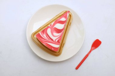 Çilek üçgenli leziz ve sulu bir cheesecake dilimi beyaz bir tabakta beyaz bir arka planı izole eder.