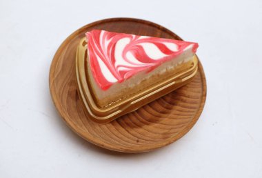 Çilek üçgenli leziz ve sulu bir cheesecake dilimi. Tahta bir tabakta dilimle. Beyaz arka plan görüntüsünü izole et.