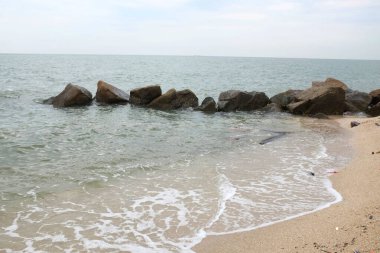 Mavi bir okyanus dalgalarının güzel manzarası sahildeki kayalara sertçe çarptı. Kayalara püskürtüldü. Taşlara su sıçrıyor. Bangsaen, Chonburi Tayland 'dan bir sahil fotoğrafı.