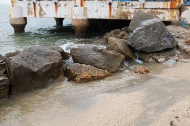 Mavi bir okyanus dalgalarının güzel manzarası sahildeki kayalara sertçe çarptı. Kayalara püskürtüldü. Taşlara su sıçrıyor. Bangsaen, Chonburi Tayland 'dan bir sahil fotoğrafı.
