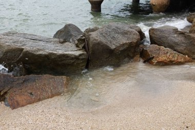 Mavi bir okyanus dalgalarının güzel manzarası sahildeki kayalara sertçe çarptı. Kayalara püskürtüldü. Taşlara su sıçrıyor. Bangsaen, Chonburi Tayland 'dan bir sahil fotoğrafı.