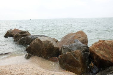 Mavi bir okyanus dalgalarının güzel manzarası sahildeki kayalara sertçe çarptı. Kayalara püskürtüldü. Taşlara su sıçrıyor. Bangsaen, Chonburi Tayland 'dan bir sahil fotoğrafı.