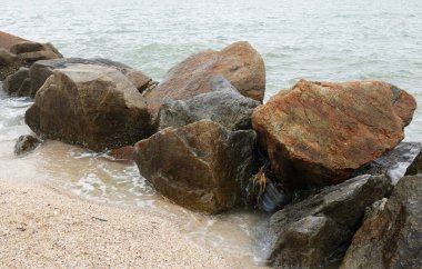 Mavi bir okyanus dalgalarının güzel manzarası sahildeki kayalara sertçe çarptı. Kayalara püskürtüldü. Taşlara su sıçrıyor. Bangsaen, Chonburi Tayland 'dan bir sahil fotoğrafı.