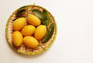  Taze olgun Marian eriği Thai meyvesi ahşap tepsilerde izole edilmiş beyaz bir zemin üzerinde (mayongchid akçaağaç eriği ve erik mangosu, Tayland). Tayland 'ın sağlıklı meyveleri