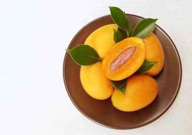  Taze olgun Marian erik meyvesi beyaz bir arkaplanda izole edilmiş bir tabakta (mayongchid maprang marian eriği ve erik mangosu, thailand). Tayland 'ın sağlıklı meyveleri