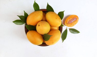  Taze olgun Marian erik meyvesi beyaz bir arka planda izole edilmiş bir kasede (mayongchid maprang marian eriği ve erik mangosu, thailand). Tayland 'ın sağlıklı meyveleri