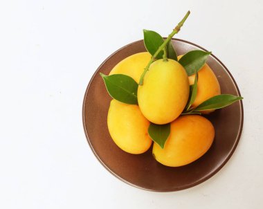  Beyaz bir zemin üzerinde izole edilmiş seramik tabaklar içinde taze, olgun Marian eriği ve erik mangosu, Tayland). Tayland 'ın sağlıklı meyveleri