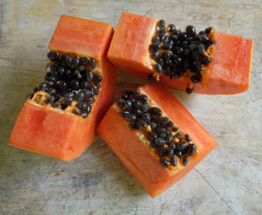 Üst ve düz taze, olgun bir papaya meyvesi uzanıyor tohumlarla, yemek dokusuyla, kesilmiş, dilimlenmiş meyvelerle ahşap kesim tahtasına. Sağlıklı beslenme için sebze ve meyve