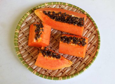 Üst ve düz taze, olgun bir papaya meyvesi uzanıyor tohumlarla, yemek dokusuyla, kesilmiş, dilimlenmiş meyveler ahşap tepside izole edilmiş. Sağlıklı beslenme için sebze ve meyve