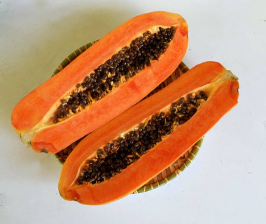Üst ve düz taze, olgun bir papaya meyvesi uzanıyor tohumlarla, yemek dokusuyla, kesilmiş, dilimlenmiş meyveler ahşap tepside izole edilmiş. Sağlıklı beslenme için sebze ve meyve