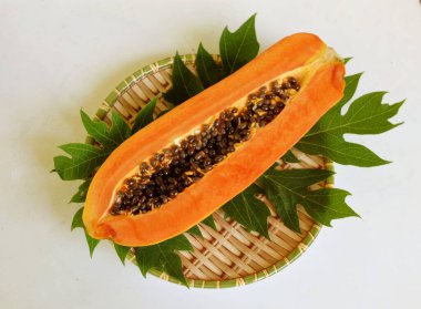 Üst ve düz taze, olgun bir papaya meyvesi uzanıyor tohumlarla, yemek dokusuyla, kesilmiş, dilimlenmiş meyveler ahşap tepside izole edilmiş. Sağlıklı beslenme için sebze ve meyve