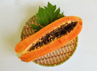 Üst ve düz taze, olgun bir papaya meyvesi uzanıyor tohumlarla, yemek dokusuyla, kesilmiş, dilimlenmiş meyveler ahşap tepside izole edilmiş. Sağlıklı beslenme için sebze ve meyve