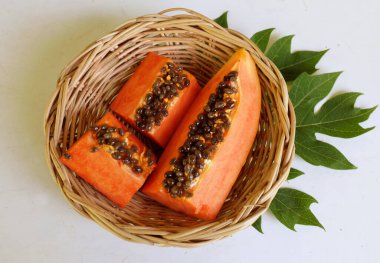 Üst ve düz taze, olgun bir papaya meyvesi uzanıyor tohumlarla, yemek dokusuyla, kesilmiş, dilimlenmiş meyveyle ahşap bir sepette yalıtılmış. Sağlıklı beslenme için sebze ve meyve